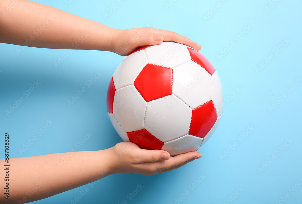 Hands with soccer ball on light blue background