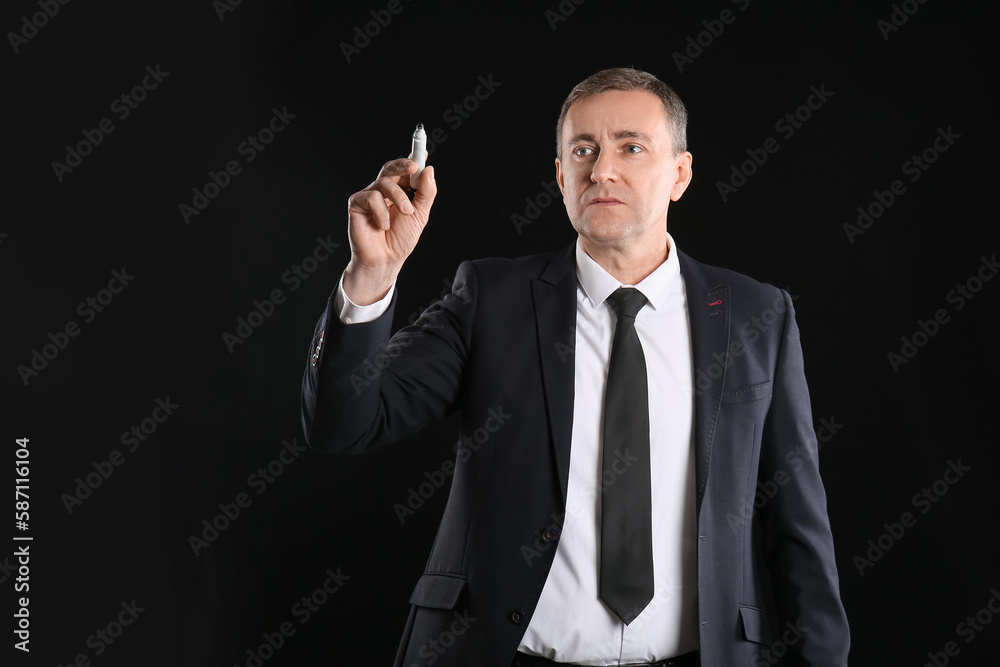 Mature business consultant with marker using virtual screen on dark background