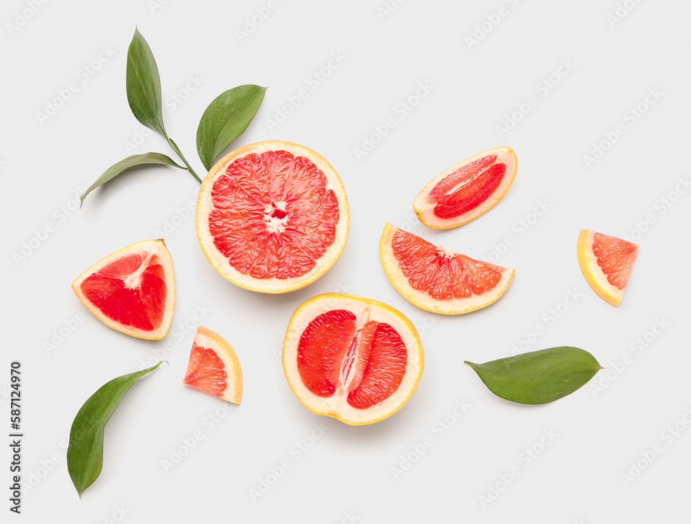 Composition with pieces of juicy grapefruit and plant leaves on white background