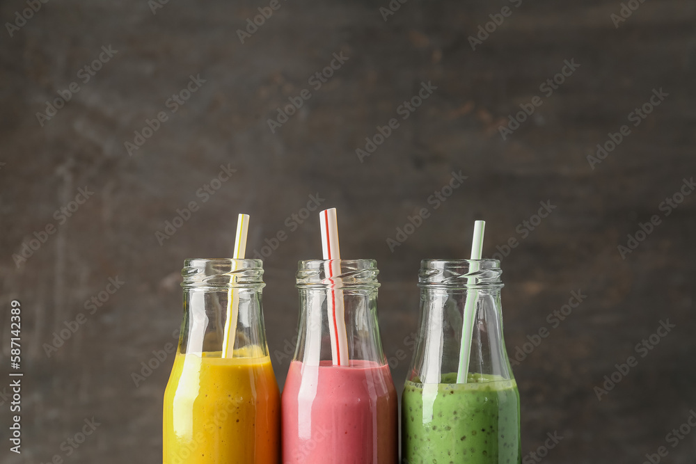 Bottles of colorful smoothie on dark background