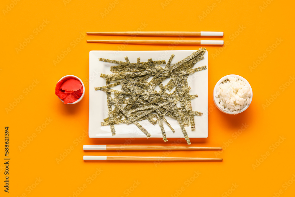Plate with cut nori sheets, rice, ginger and chopsticks on color background