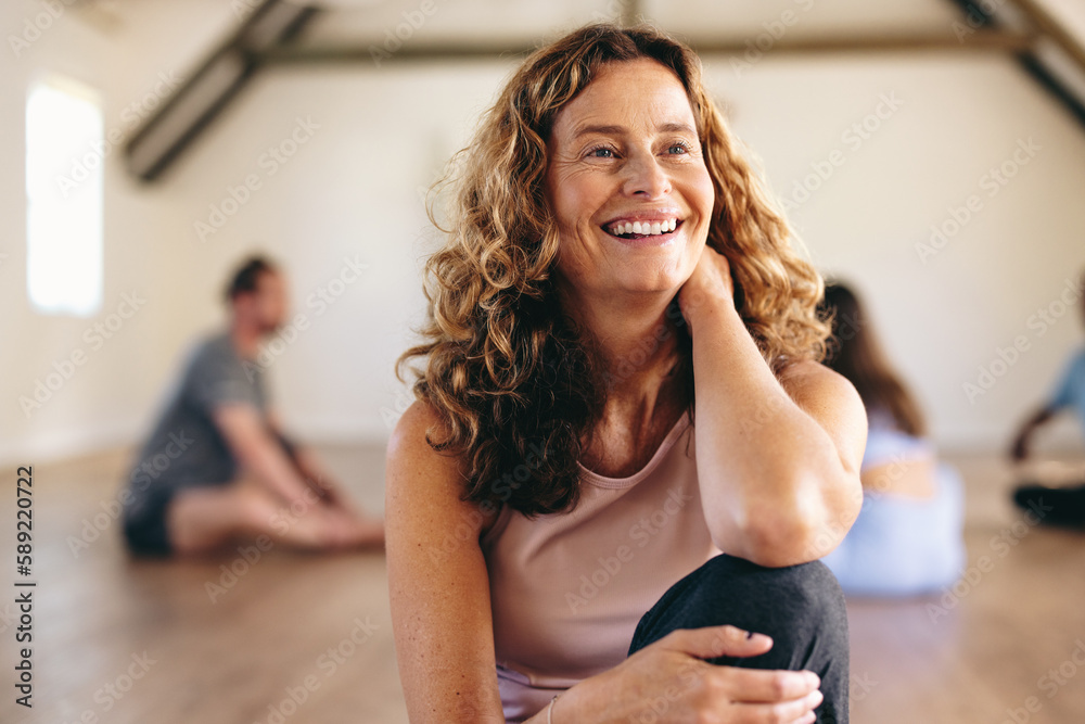 Senior woman sitting in a yoga studio with her class