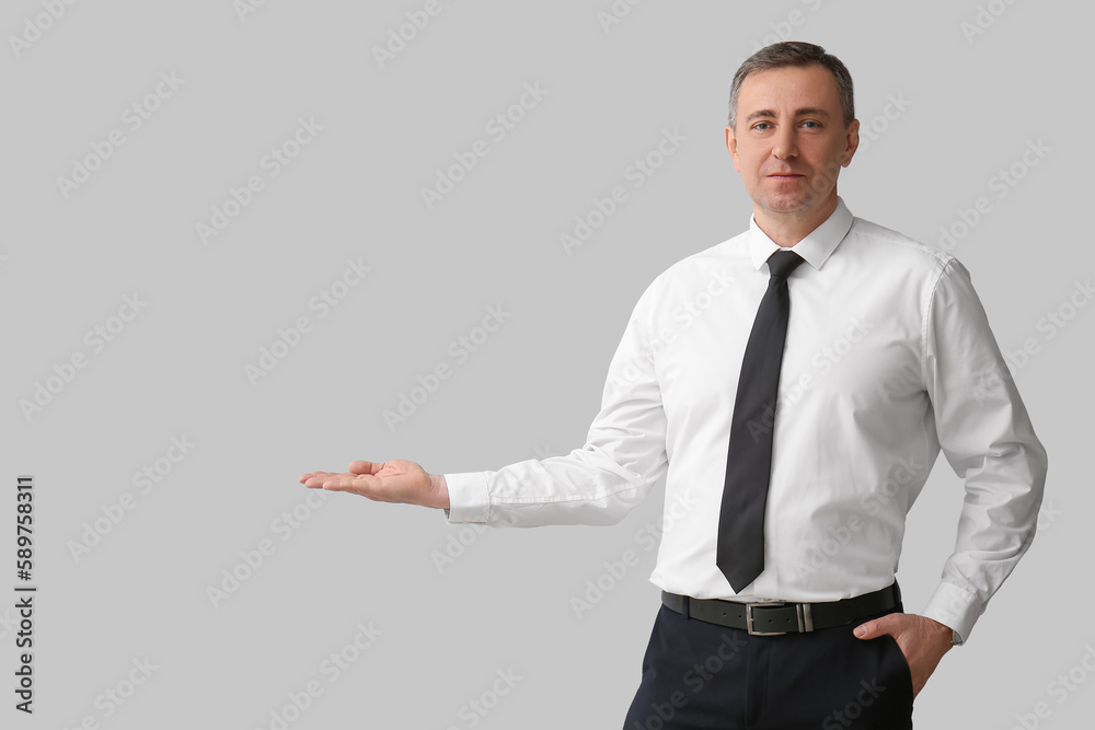 Mature business consultant showing something on light background