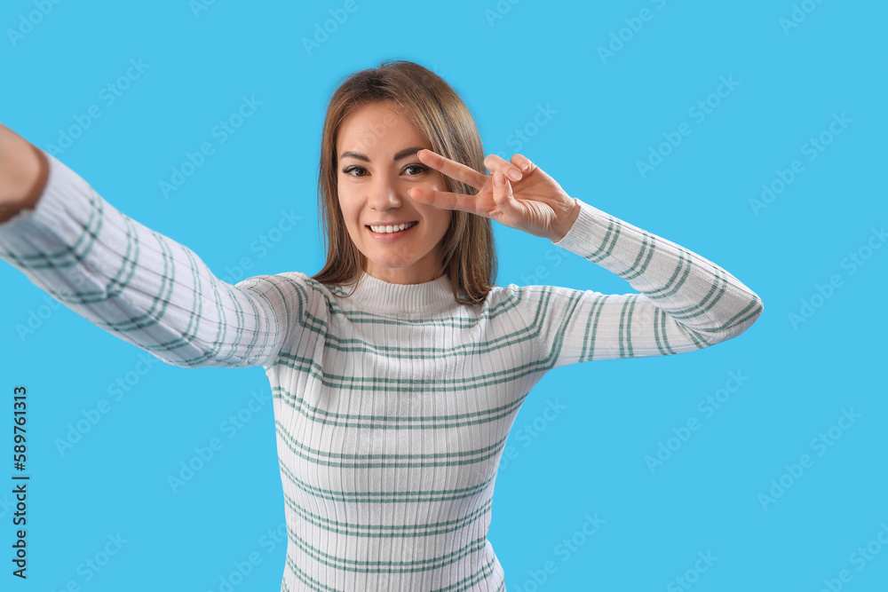 Beautiful woman taking selfie on blue background