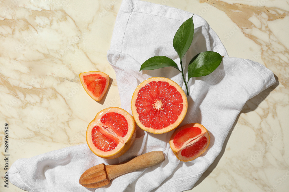 Composition with cut ripe grapefruits, juicer and plant branch on light background
