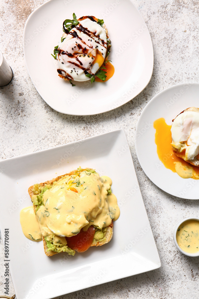 Plates with delicious eggs Benedict on white table