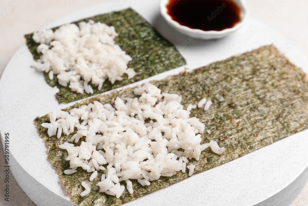 Wooden board of nori with rice on light background, closeup