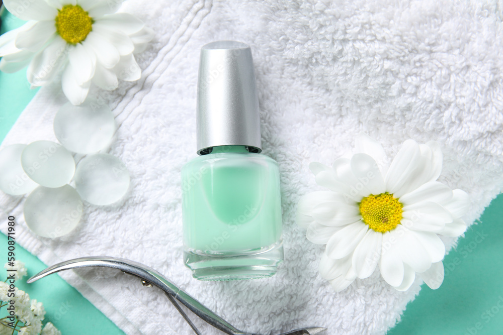 Composition with bottle of cuticle oil, towel and flowers on color background, closeup