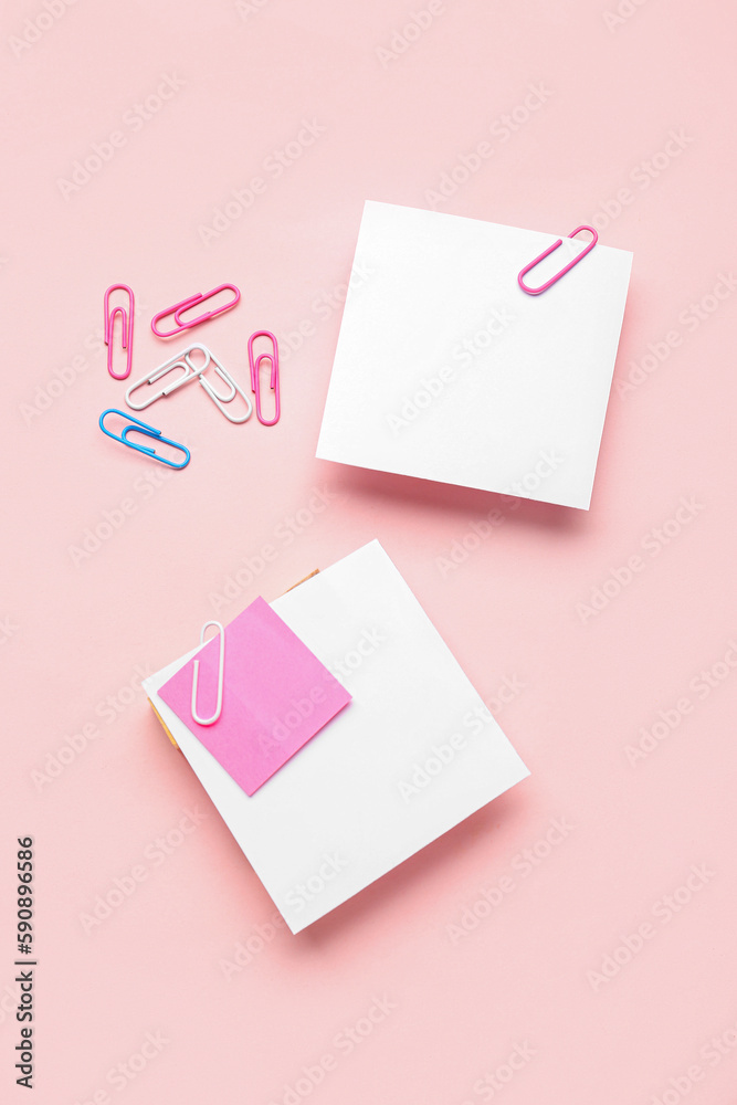 Sticky notes with paper clips on pink background