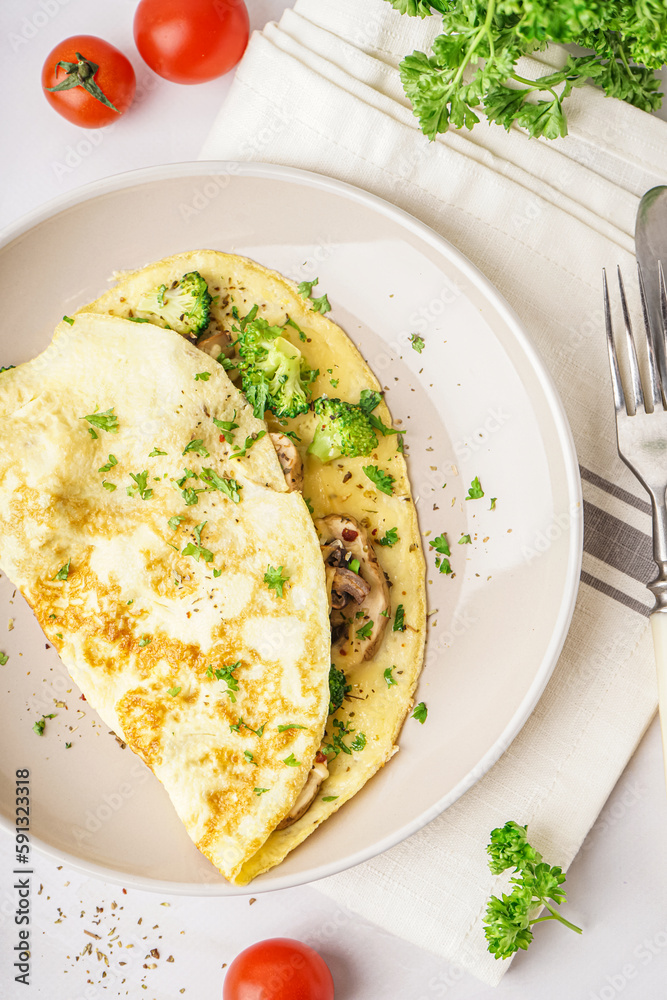 Tasty omelet with broccoli and mushrooms on light table