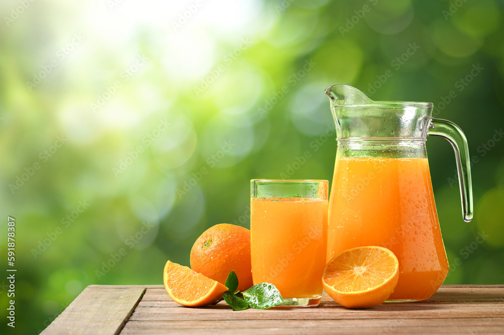 Natural squeezed orange juice on woodentable with blur green background.