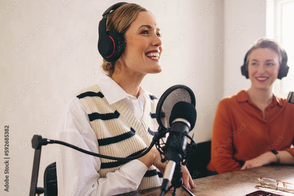 Happy female podcaster presenting a guest on her show