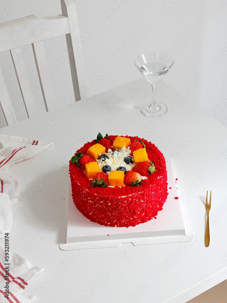 Vertical shot of Red Velvet cake decorated with berries on white table