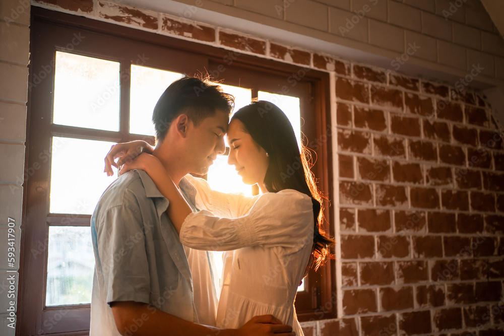 Asian young man and woman looking each other in living room at home. 