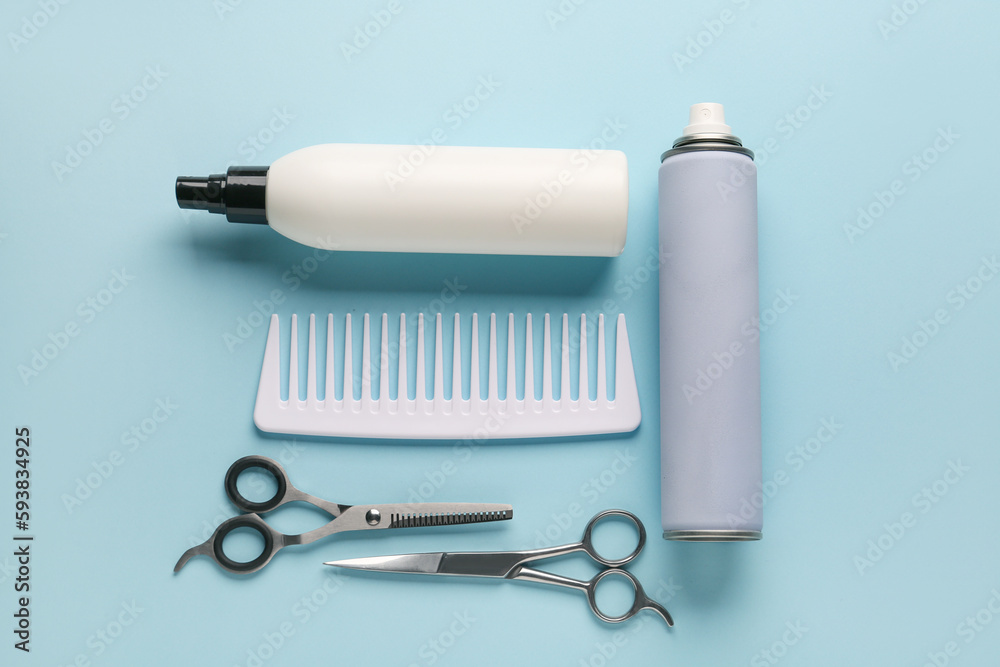 Composition with bottles of hair sprays, comb and scissors on color background