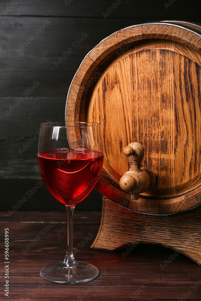 Oak barrel and glass of wine on dark wooden background
