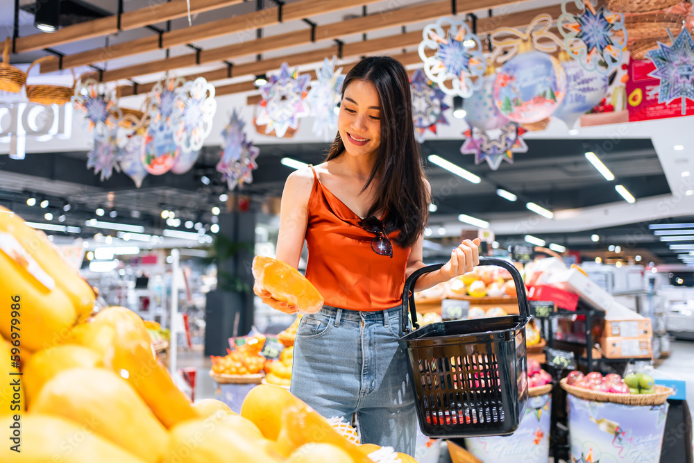 Asian young beautiful woman holding grocery basket walk in supermarket.