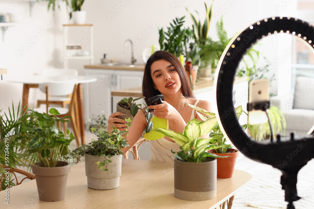 Female blogger with houseplant taking video at home