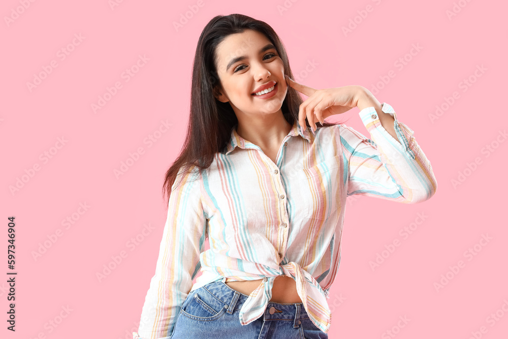 Young woman in shirt smiling on pink background