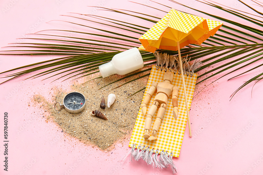Composition with seashells, compass, palm leaf and wooden mannequin lying on beach towel against pin