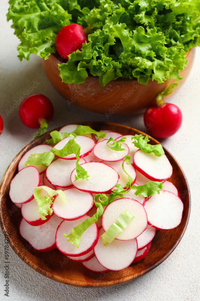 Bowls with fresh slices of radish and lettuce on white background