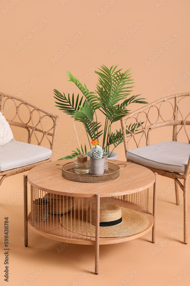 Wooden coffee table with houseplant and cozy armchairs on beige background
