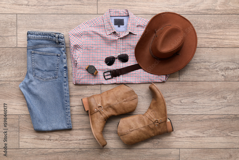 Male clothes with cowboy boots and accessories on wooden floor