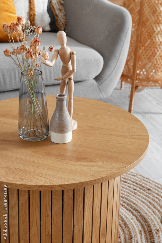 Wooden mannequin and vase with dried flowers on coffee table in interior of living room