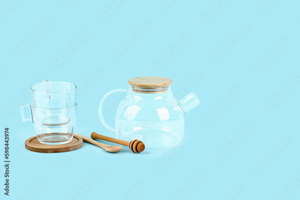 Teapot, cups, spoon and honey dipper on blue background