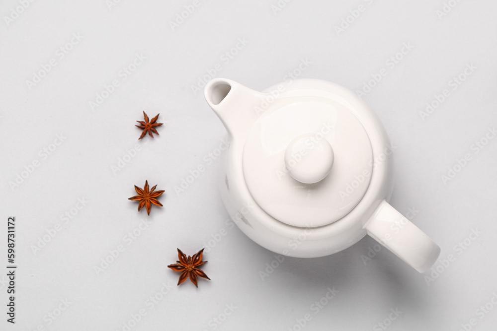 Ceramic teapot with spices on grey background