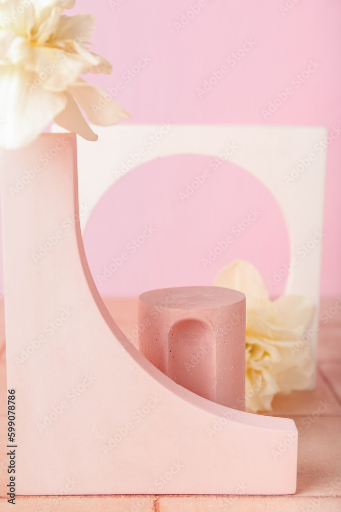 Decorative plaster podiums with daffodils on tile against pink wall