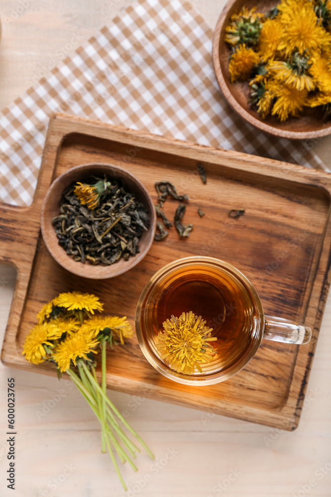 Board with bowl and glass cup of healthy dandelion tea on white wooden background
