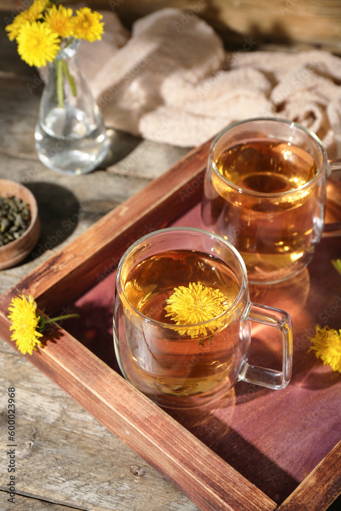 Board with glass cups of healthy dandelion tea on wooden table