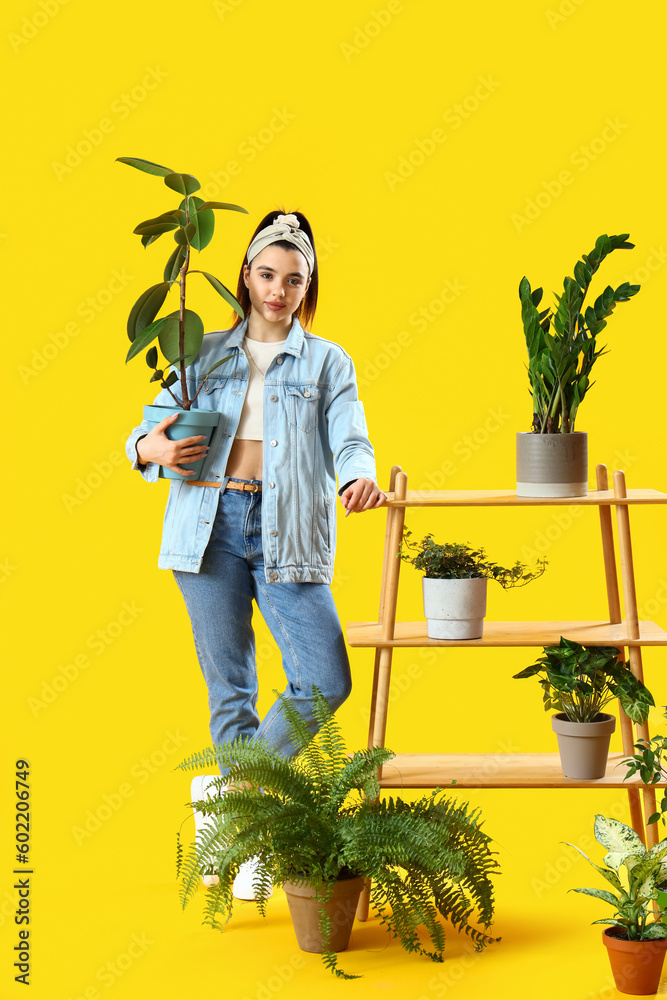 Young woman and shelving unit with green houseplants on yellow background