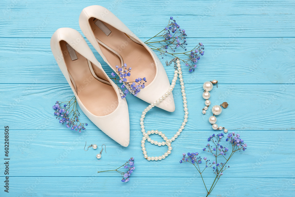 Composition with stylish female accessories, heels and gypsophila flowers on color wooden background