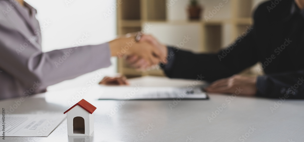 Real estate agents shake hands after reaching an agreement and signing a legal home purchase.