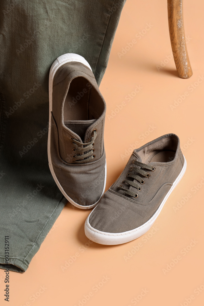Sportive male shoes and jeans on pale orange background
