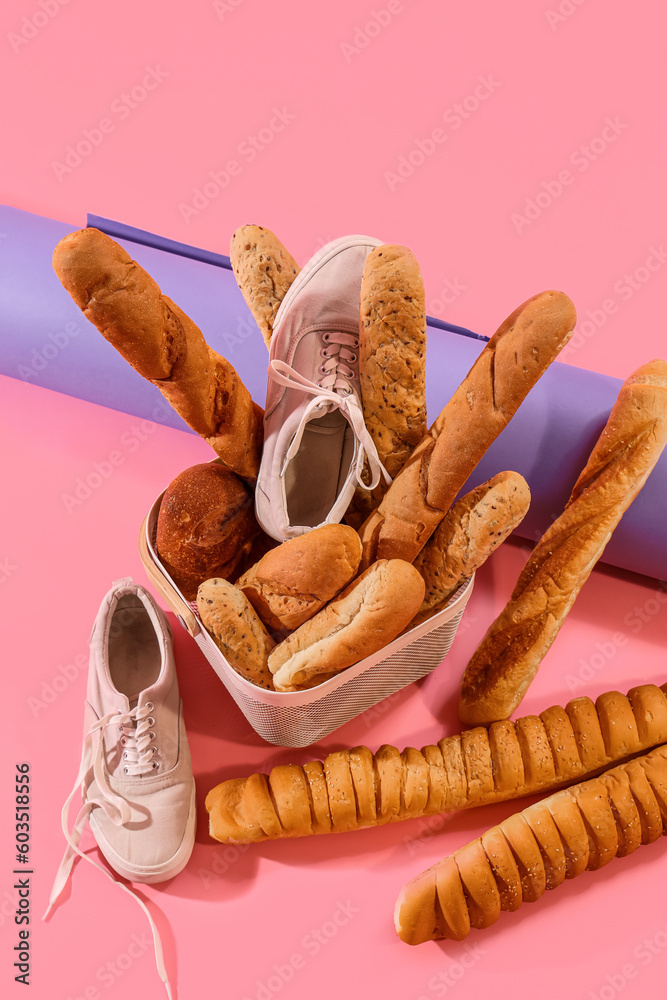 Sportive male sneakers with basket of bread on pink background