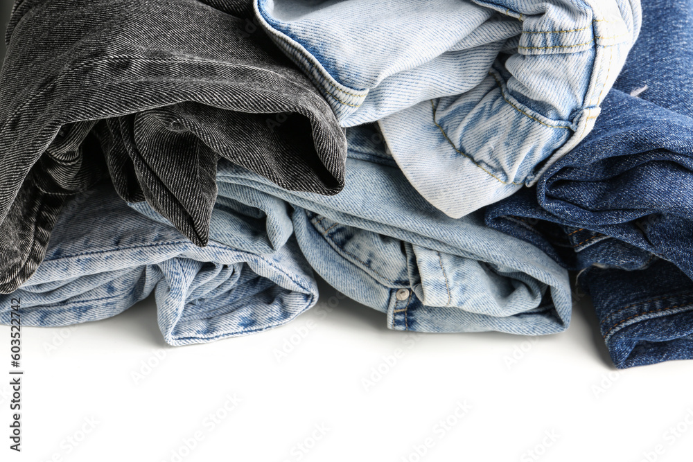 Different rolled jeans on white wooden background