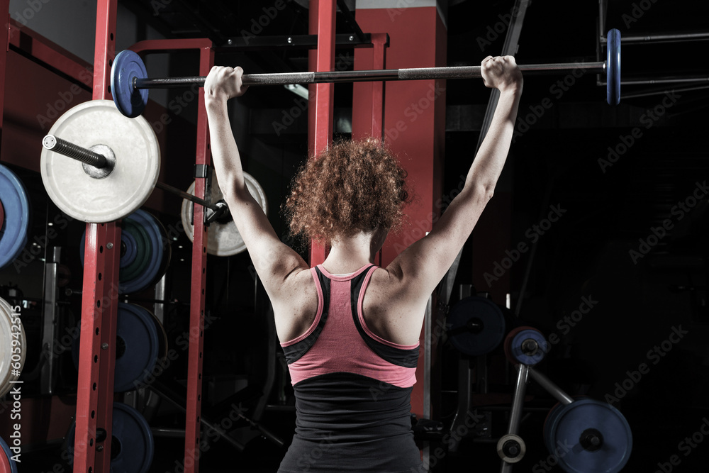 Woman bodybuilder engaged with a barbell in the gym