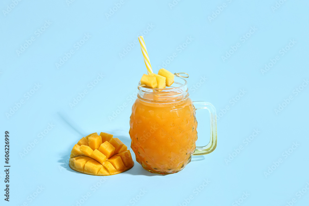 Mason jar of fresh mango smoothie on blue background
