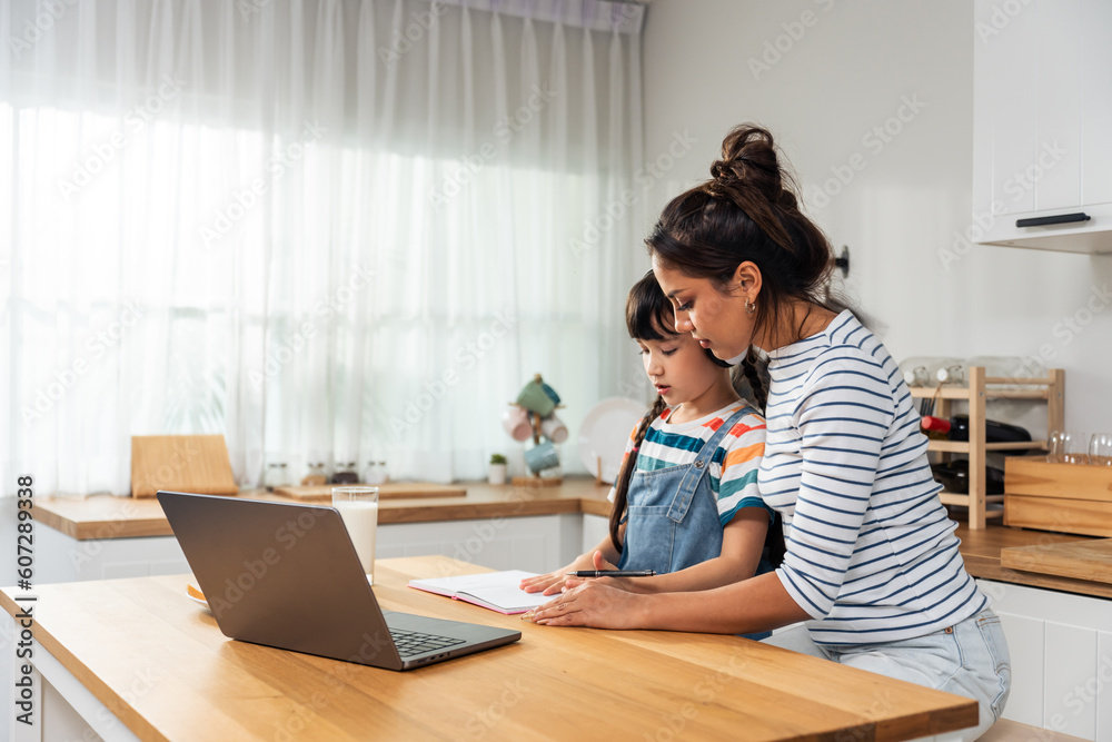 Caucasian young girl kid learning online class at home with mother. 