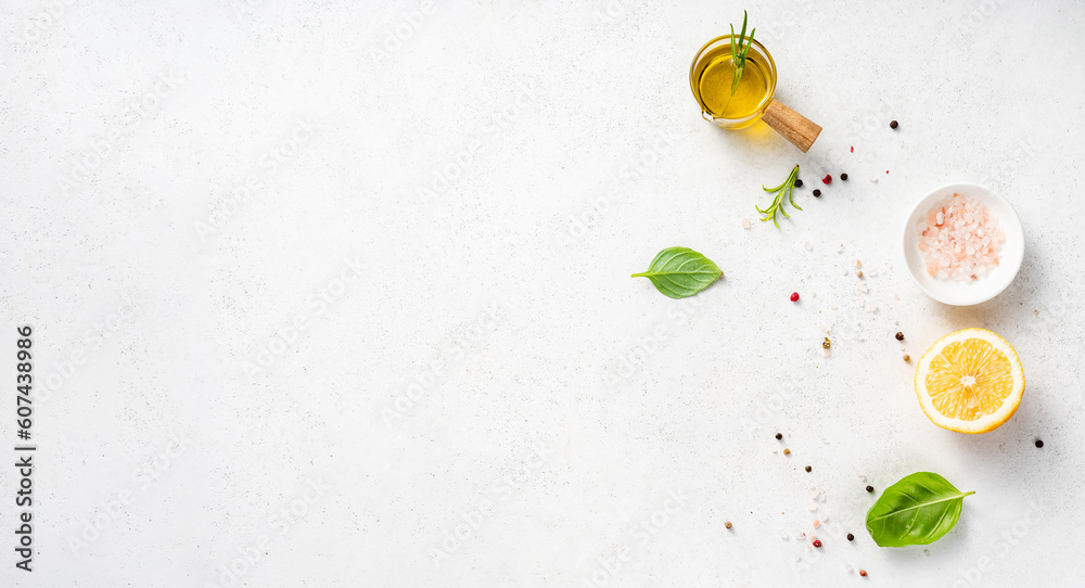 Various herbs and spices, oil in glass bowl and half of lemon on a white concrete background. Backgr