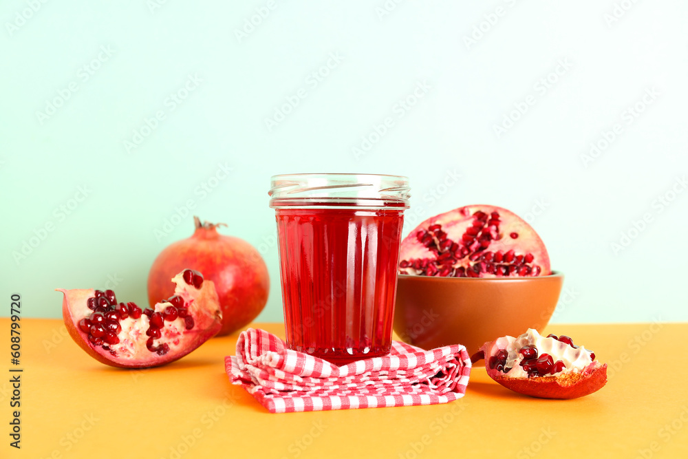 Bowl with fresh pomegranate and glass of juice on colorful background