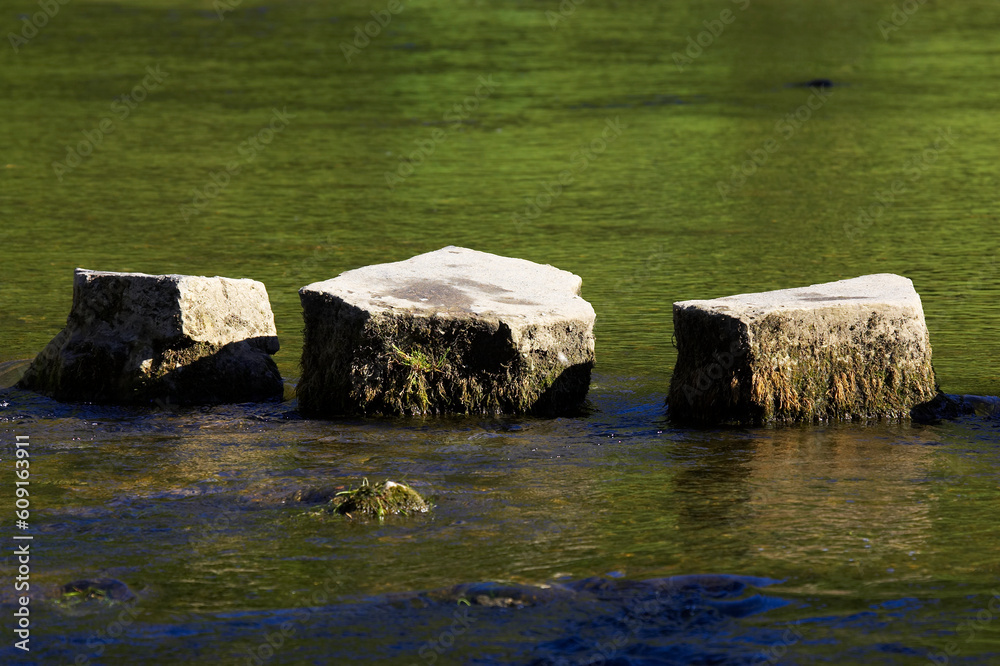 3 stepping stones in river, dovedale, peak district, uk