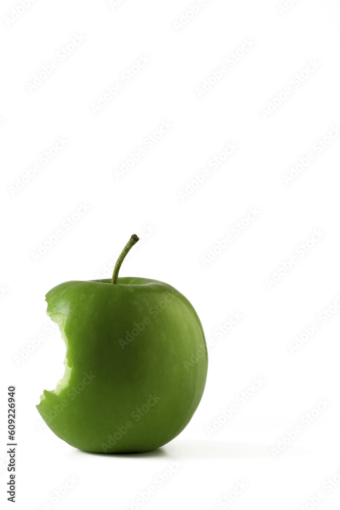 Isolated green apple with a bite taken from it located in bottom left hand corner with plenty of spa