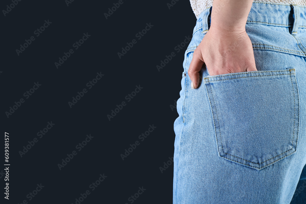Young woman in stylish jeans on dark background, back view