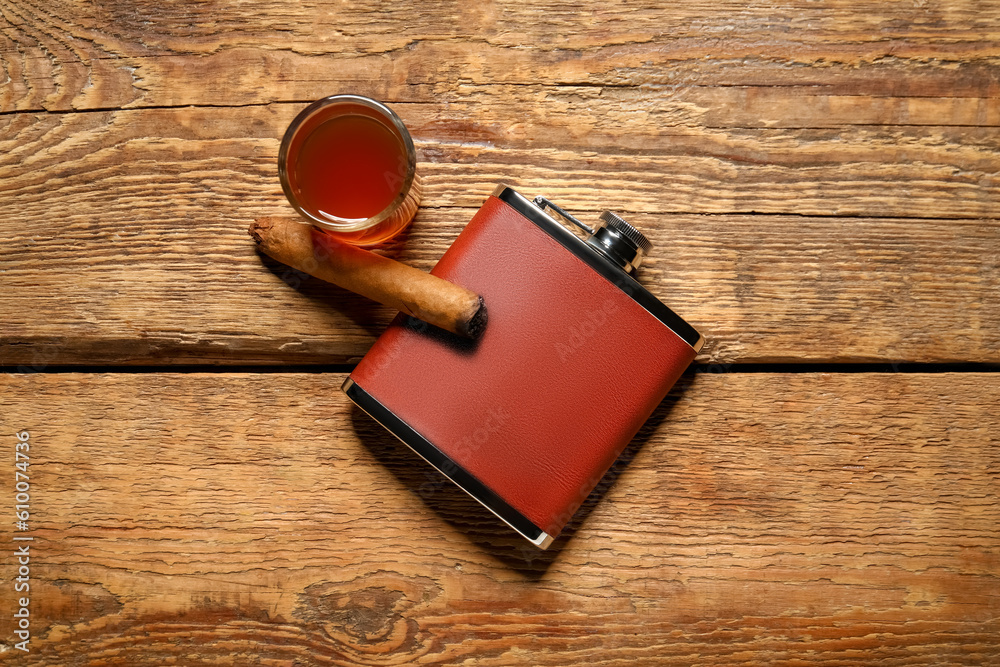 New hip flask, glass of whiskey and cigar on wooden background