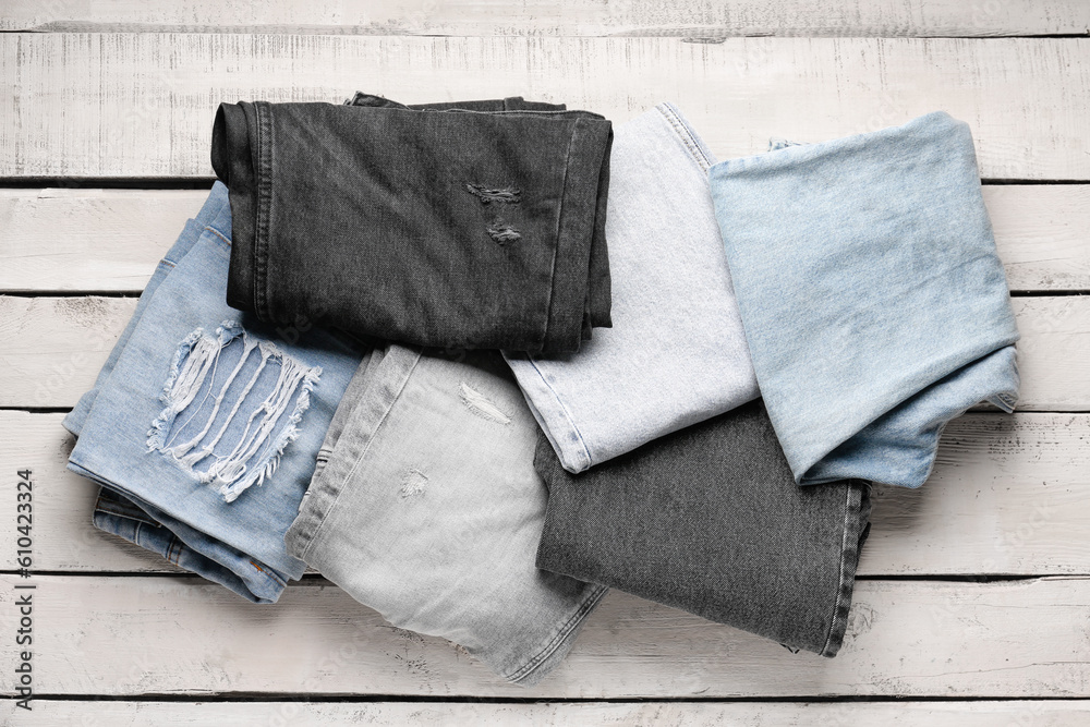 Different stylish denim jeans on wooden background