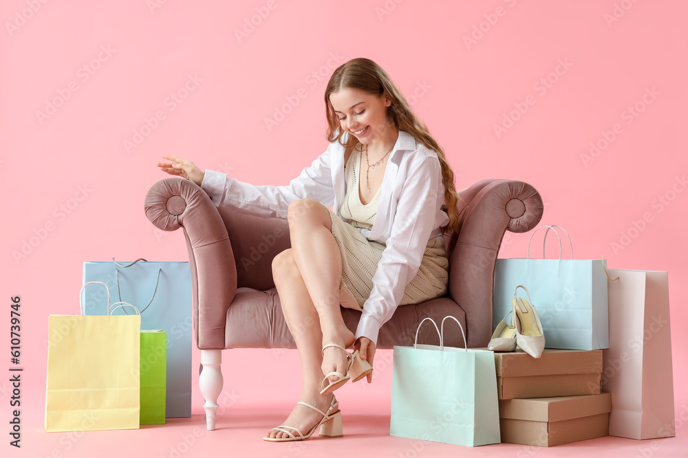 Young woman trying new shoes on pink background
